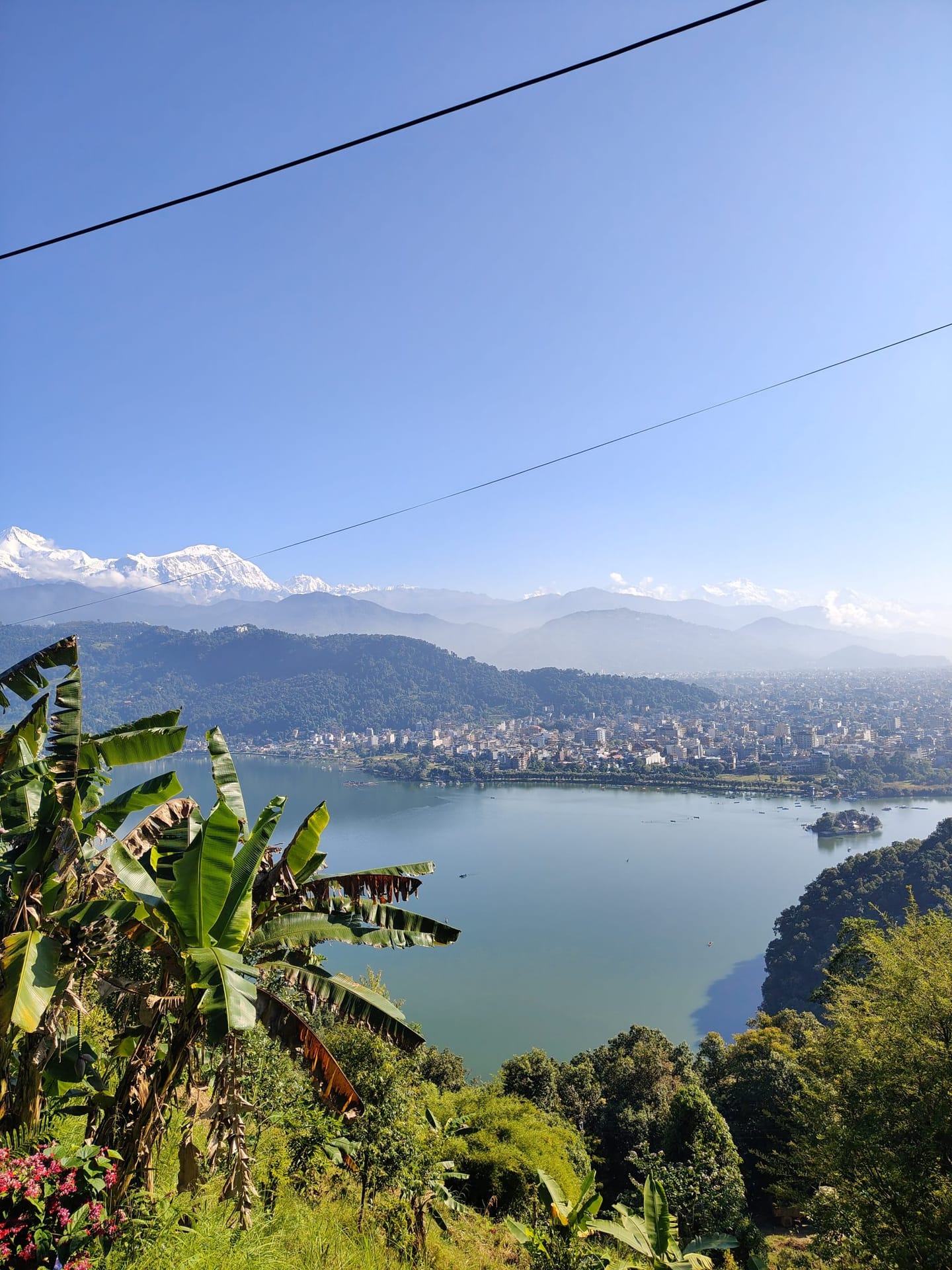 Phewa lake and the lakeside city of Pokhara seen from the hills above, with the Annapurna range beyond