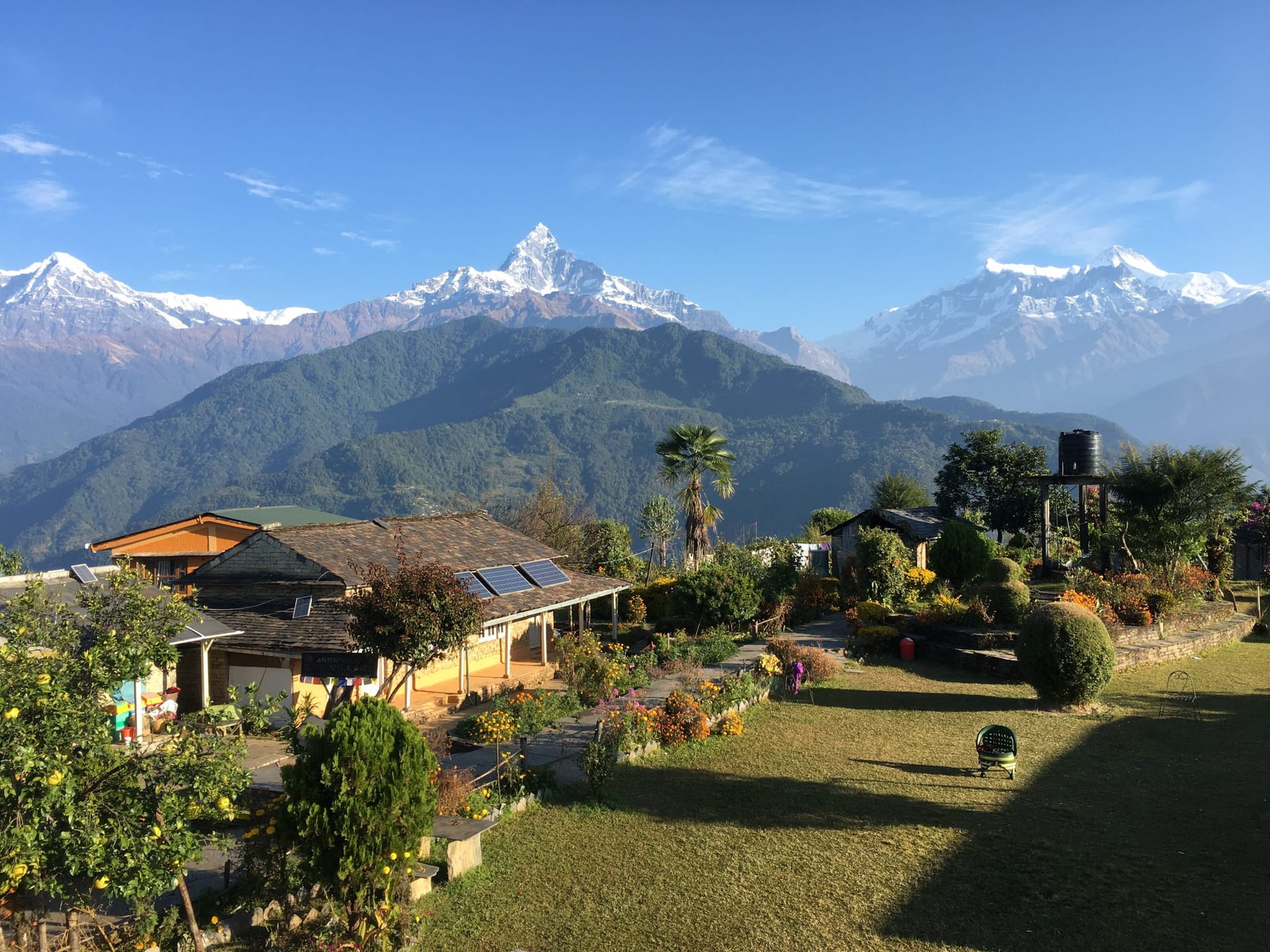 A village lodge at Astam in the Annapurna foothills, its garden in flower, with Machapuchare and the Annapurna range behind
