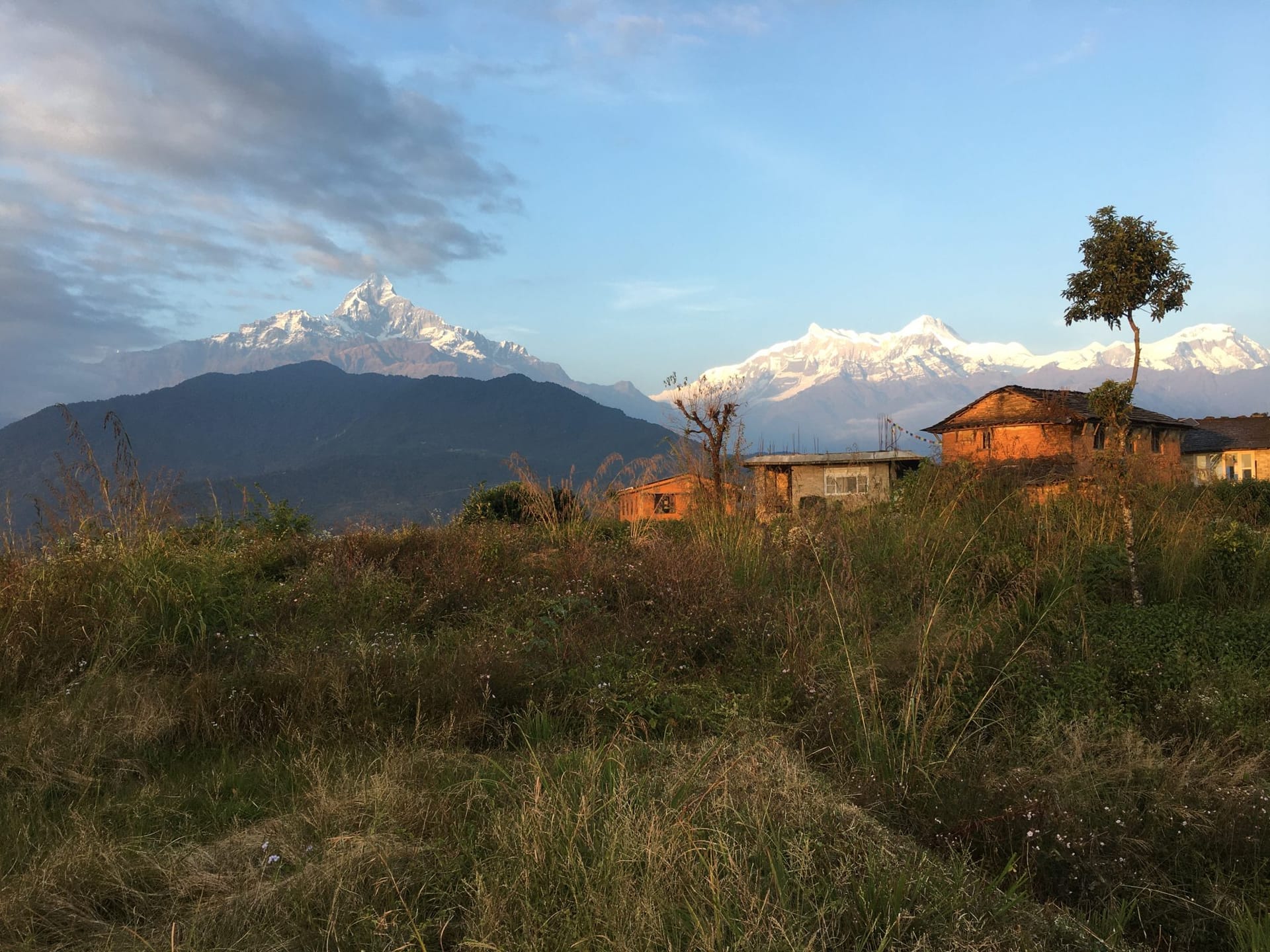 Village houses in morning light on a ridge below Machapuchare and the Annapurna range